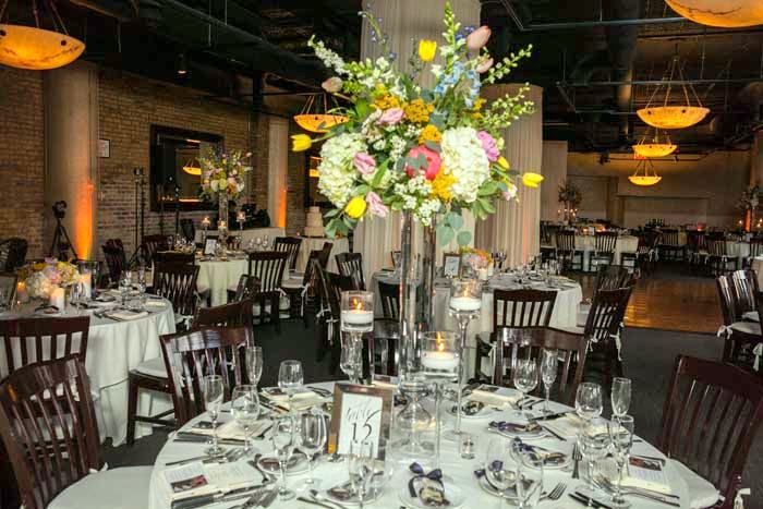An intimate wedding reception with candlelit tables and tall floral centerpieces